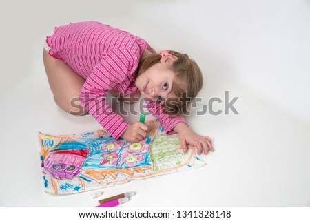 Little girl with pigtails paints a picture of felt-tip pens on a white background.