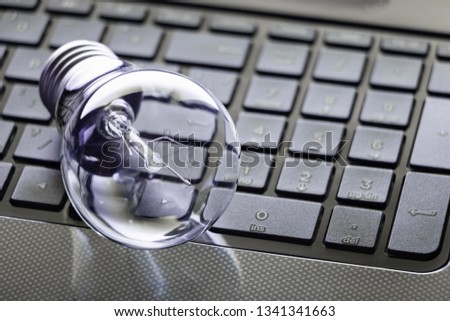 Glass light bulb with a spiral lies on the keyboard.
