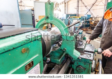 Turner worker manages the metalworking process of mechanical cutting on a lathe
