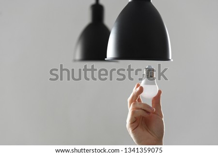 Changing the bulb for led bulb in floor lamp in black colour. On light gray background. Royalty-Free Stock Photo #1341359075