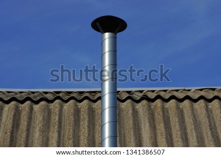 long metal pipe on a gray slate roof against a blue sky