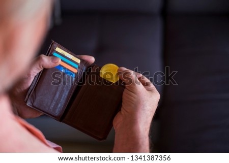 senior taking a gold bitcoin of his wallet - indoor - future payment and money concept