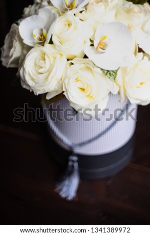 Gift box full of beautiful white roses and orchids on dark wooden background with copyspace