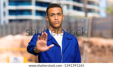 Young afro american worker man making stop gesture denying a situation that thinks wrong in a construction site