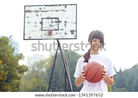 teenage girl holding basket ball in school court
