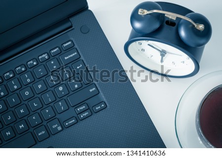 a work desk with a computer and office accessories and an alarm clock measuring the time running away. The concept of urgent deadlines at work