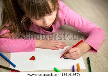 Child girl drawing with colorful pencils crayons heart on white paper. Art education, creativity concept.