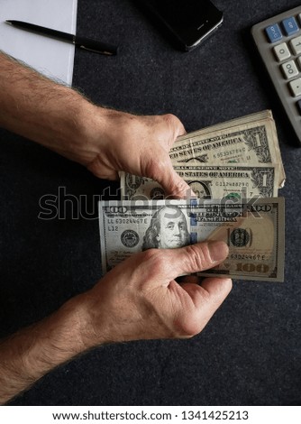 hands of an older man holding american dollars banknotes