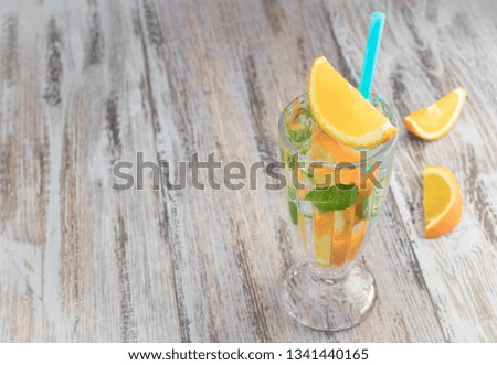 Citrus refreshing drink in a glass goblet on a wooden table. summer refreshing cocktail. Healthy food, drinks. orange and mint ice water. Copy space. horizontal view.