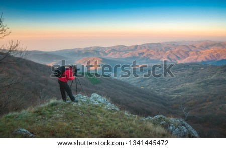 Photographer with a camera on tripod in a mountain valley.