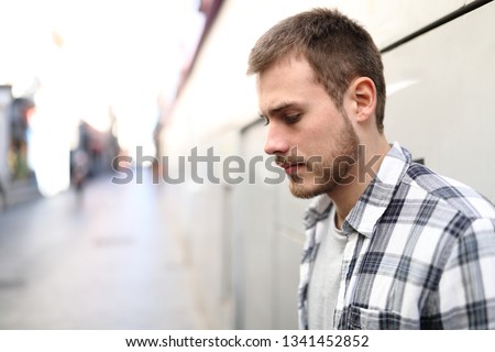 Side view portrait of a sad man complaining alone in the street Royalty-Free Stock Photo #1341452852