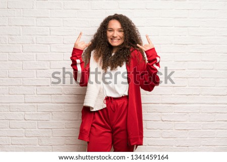 Teenager sport girl with curly hair making rock gesture