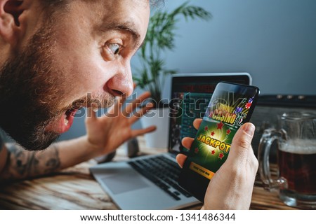 Lucky man celebrating victory after winning jackpot in online casino. Royalty-Free Stock Photo #1341486344