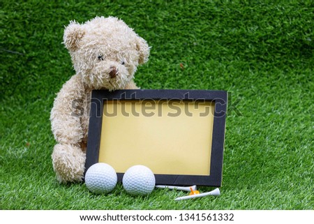 Bear golfer with blank board and golf ball on green grass