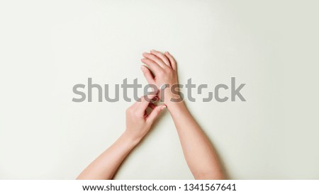 Woman hands and cream droplet on light green background.