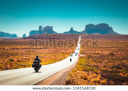 Classic panorama view of motorcyclist on historic U.S. Route 163 running through famous Monument Valley in beautiful golden evening light at sunset in summer, Utah, USA Royalty-Free Stock Photo #1341568130