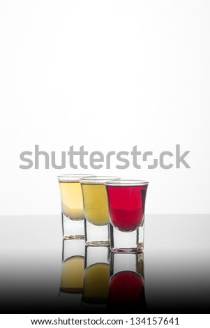 Filled shot glasses on reflective surface