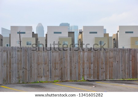 Modern townhomes rise behind a wooden fence.