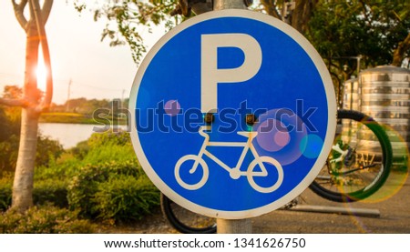 Bicycle parking sign at public park in evening and bicycle hanging. The sign is old with rust screw