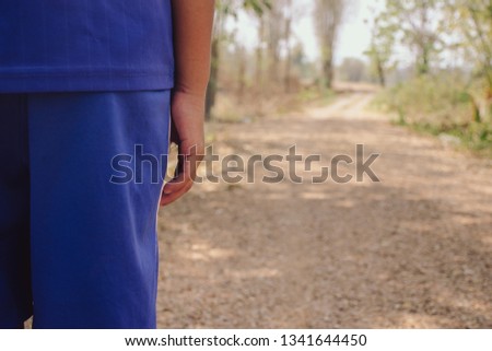 kid wearing in blue standing and looking in dirty road and arid landscape