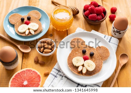 Pancakes breakfast for kids, food art. Bear or Walrus shape pancake decorated with fruit, berries and nuts on wooden table. Children meal