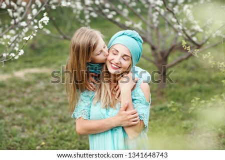 Portrait of kissing and happy mother and daughter in spring white garden.