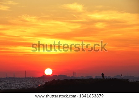 The evening sun, the sky is bright and colorful, looking out to see the picture of the chimney and the mountains. On the rocks, there are people walking around and watching the scenery.