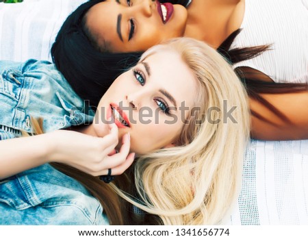 two young pretty teenager girls best friends laying on grass making selfie photo having fun, lifestyle happy people concept, students at summer close up