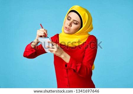   arab woman left-handed writes in notebook on a blue background                             
