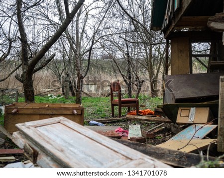 The destroyed wooden constructions. The deserted and plundered house. The broken wooden shed in the middle of garbage and ruins