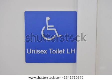 Unisex Toilet  LH Sign with on a white wall background.