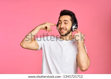   man smiling listening to music on headphones over pink background                             