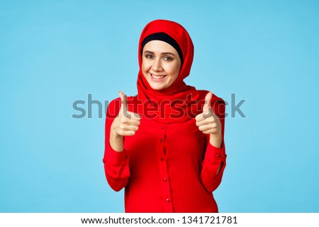   arab woman smiling on a blue background signs with fingers                             