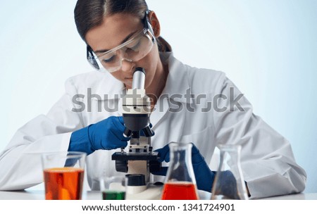 Laboratory assistant in glasses and a medical gown blue gloves microscope scientific research                          