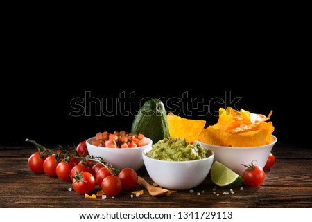 Spicy golden crispy chips with salsa and guacamole sauce on a wooden table. mexican food