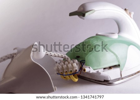 Disassembled green electric iron. The removed back part of the electrical device with access to electrical wiring. Copy space. Repair of household appliances. Close-up.