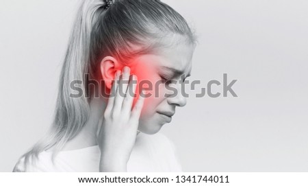 Young woman with sore ear, suffering from otitis, black and white panorama with red accent, free space Royalty-Free Stock Photo #1341744011