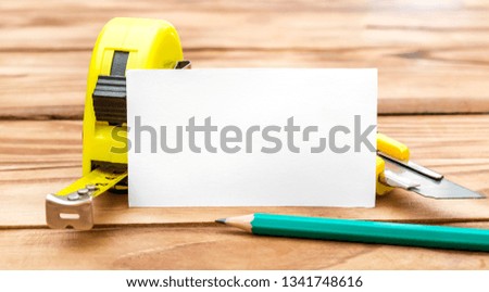 Blank business card with measuring tape tool, stationery knife and pencils on the table. Business template.