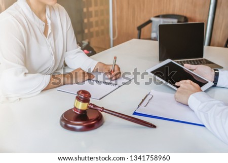 A young businessman visits a lawyer within the attorney's office to seek advice from a lawyer team about investment law and discuss legal contract documents before signing a business contract.