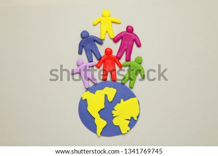 Plasticine multicolored cartoon people on globe. The use and depletion of the planet earth, overpopulation and population growth.