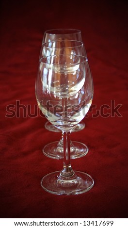 Three wine glasses in a row on red plush background with vignette