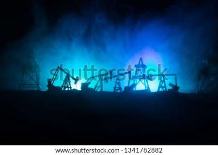 Artwork decoration. Oil pumps and oil rigs energy industrial machines for petroleum at night with fog and backlight. Energy industrial concept. Selective focus