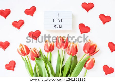 Creative flat lay top view Mothers Day greeting card with red tulips spring flowers on white background. Celebration Postcard template