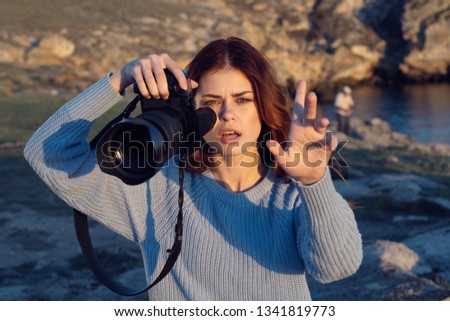 Young woman photographer in nature with a camera in hand and a large lens                     