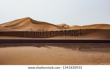 Road crossing middle of the desert.
Through desert dunes.