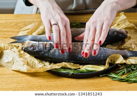 Chef cooking sea bass on a wooden table. Black background, side view, space for text