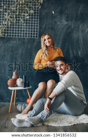 Family sitting on the studio. Blonde in a yellow sweater. Pregnant woman with her husband