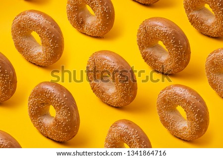 Colorful pattern with round bread bagels with sesame seeds on yellow background Royalty-Free Stock Photo #1341864716