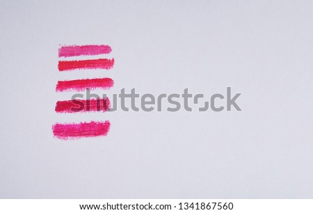 cosmetic swatches of five red shades of lipstick on white paper on the right side