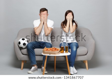 Couple woman man football fans in white t-shirt cheer up support favorite team covering face with palms isolated on grey background in studio. People emotions, sport family leisure lifestyle concept